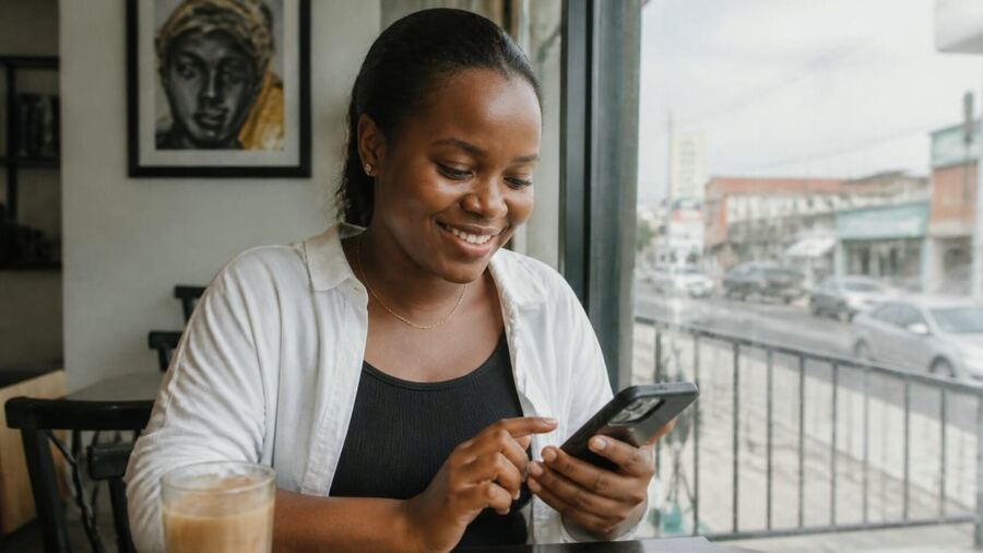 A woman in a café smiling at her phone.