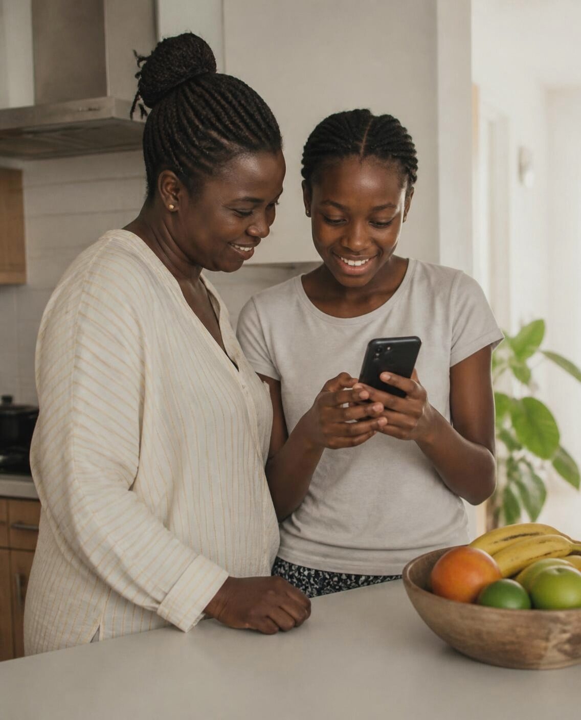 A mother and her teenage daughter looking at a phone in their kitchen.